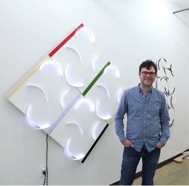 JD Walsh in his studio with (l to r) Phased Arcs, 2013, acrylic on MDF, Plexiglas, LED lights, micro controller; and 8/8, 2014, Hydrocal, wood, acrylic sheet.