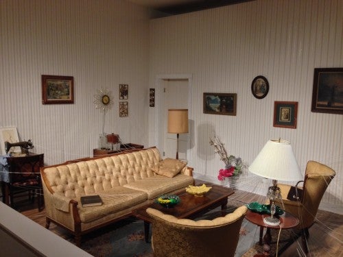 Jonathan Schipper, partial view of Slow Room, furniture, cable, pulleys, motor. Furniture and objects with string attached will be slowly pulled toward a central hole in the wall. 