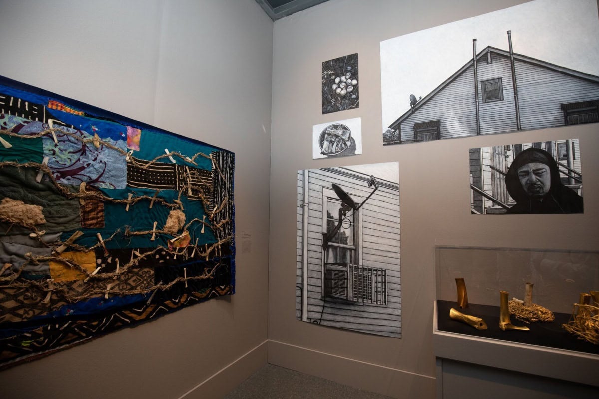 Corner of a gallery with multiple artworks by Willie Birch on the walls. 