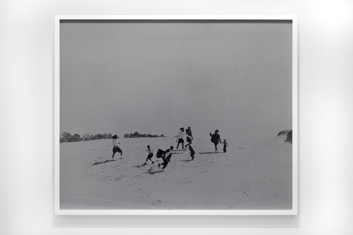 Black and white high contrast photograph of a family on a dune.