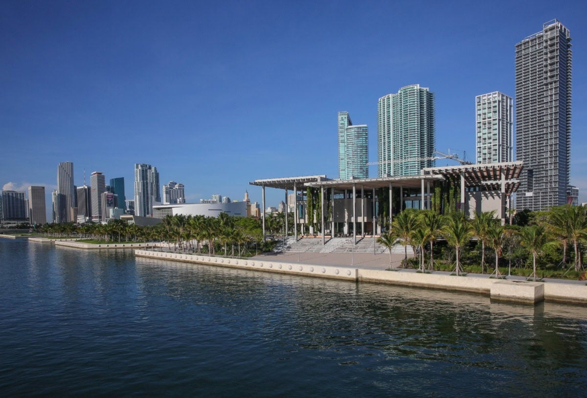 a museum building with modern architecture on the coast with the skyline behind it