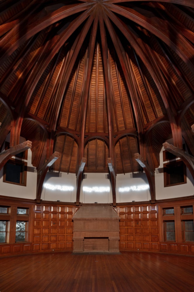 a dark wood paneled library with dates written in neon across the top of the library walls