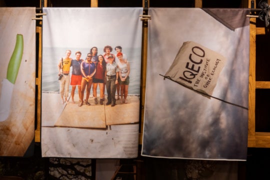 photo of screen-printed textiles showing a group of people on the shore of the beach and a flag reading 