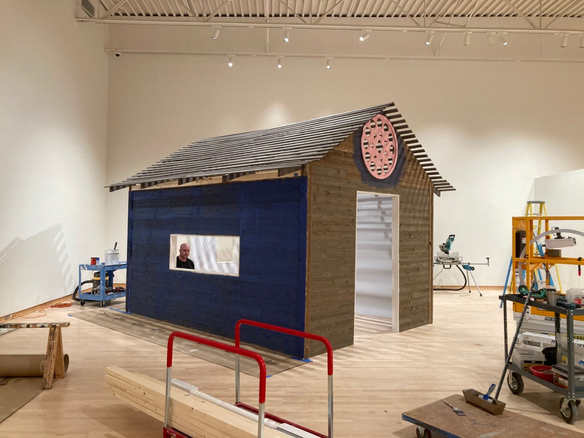 small brown house in gallery person in open windown