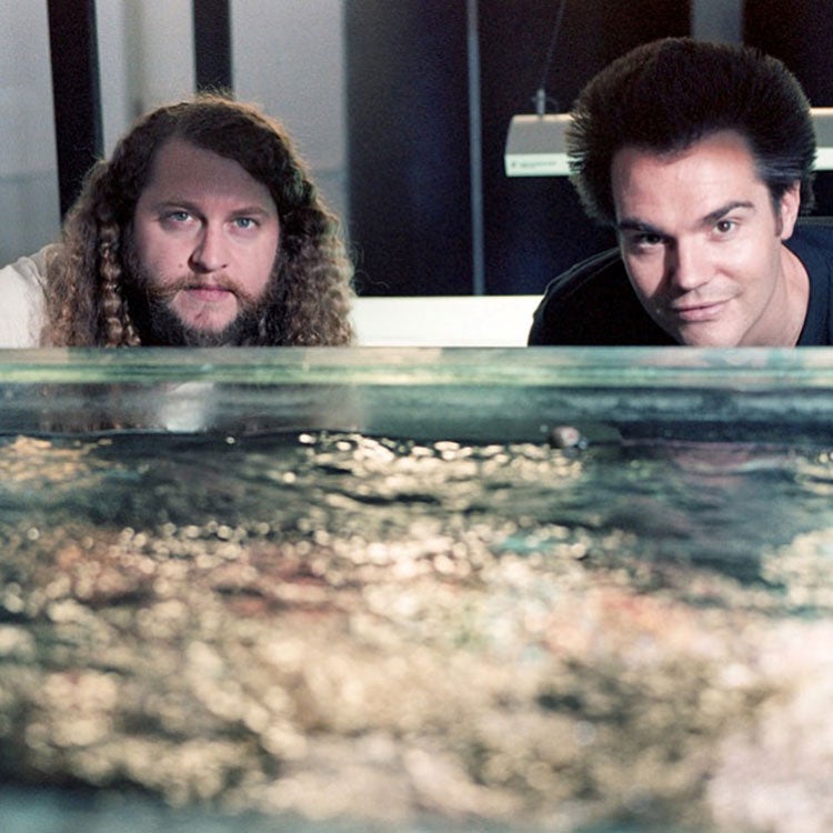 two guys lots of hair water in the foreground in laboratory