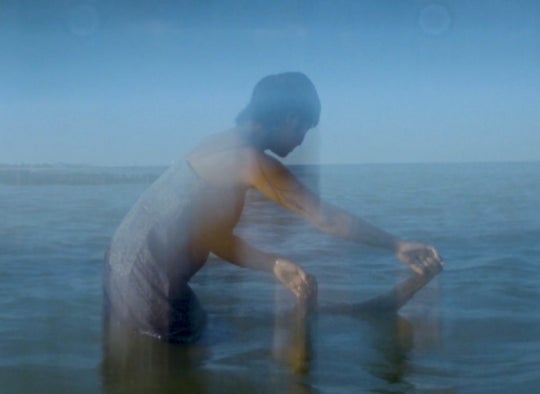 slow captured still of a person with deep blow water, back to the water's horizon