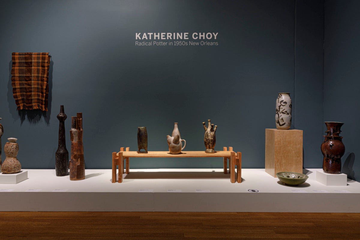 Installation view of Katherine Choy exhibiting feature ceramic pieces at a lower eye level, with a couple resting on a table and others on the direct stage of the exhibit.