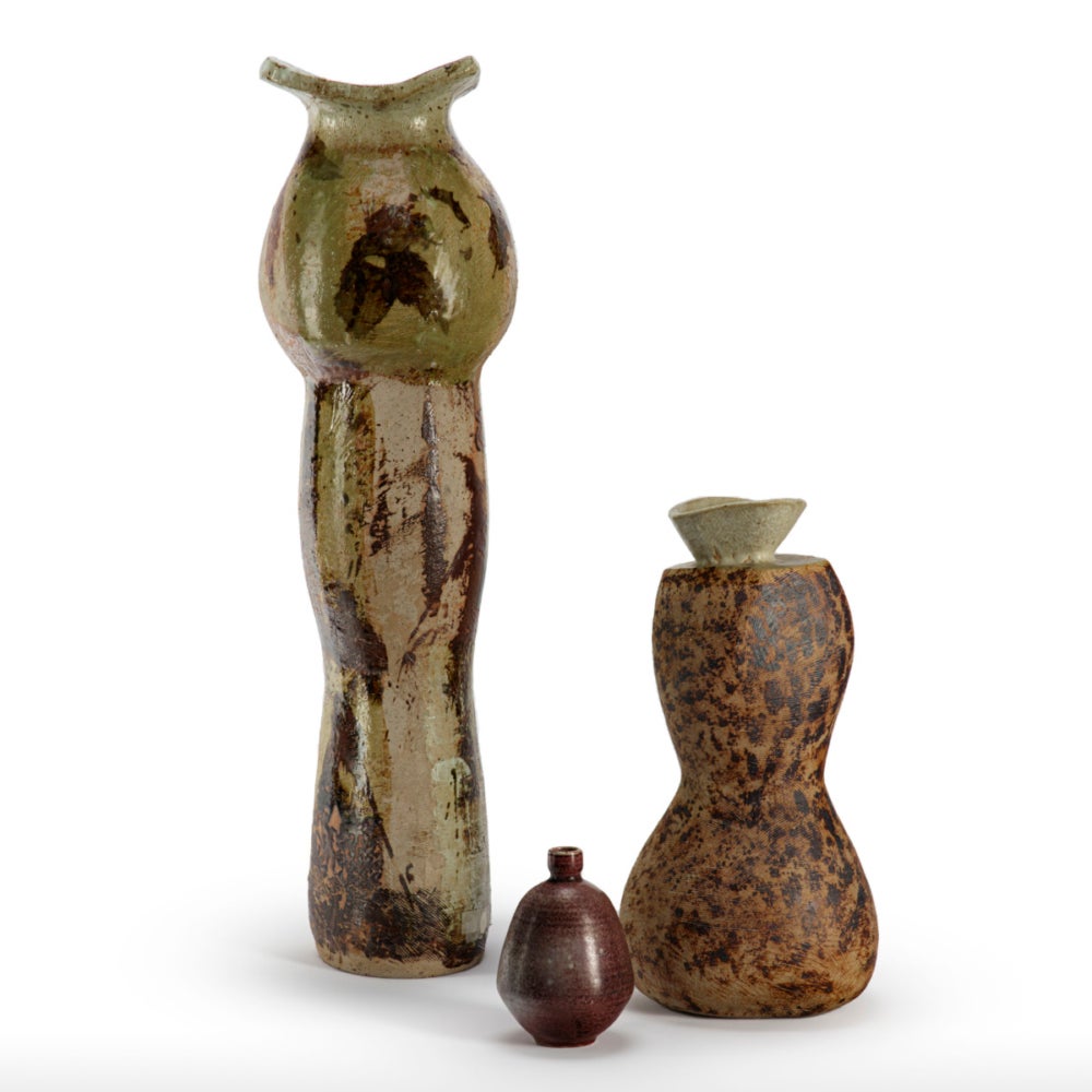 Three sculptures of varying heights and colors, some are curvier while another is rounder in shape. Each vessel has a curved entry point at the top.