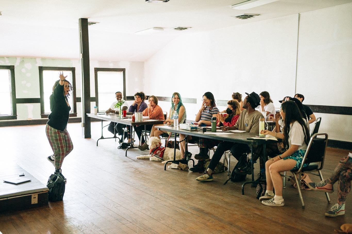 students in clusters gather to watch an instructor in motion in a bright classroom setting