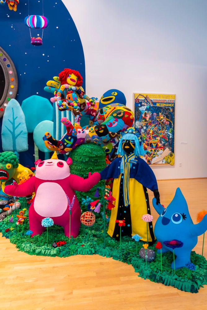 Closeup of characters standing together in artificial grass and in front of a curved, starry sky.