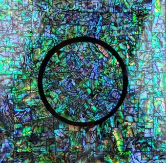 a blue green iridescent surface with a black circle outlined in the center