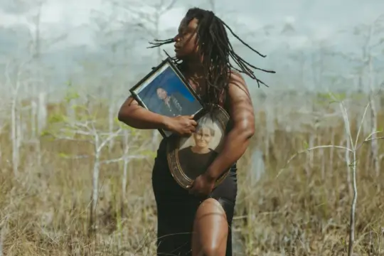 image of black woman holding frames in the middle of the everglades