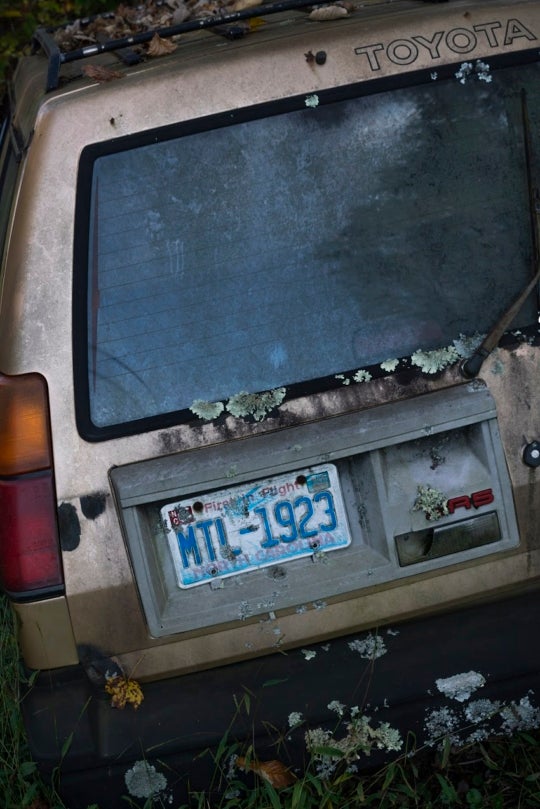 back view of an abandoned Toyota sunken into the ground